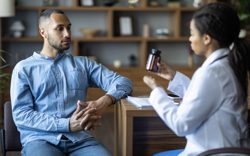 young female doctor shows young male a bottle of supplements